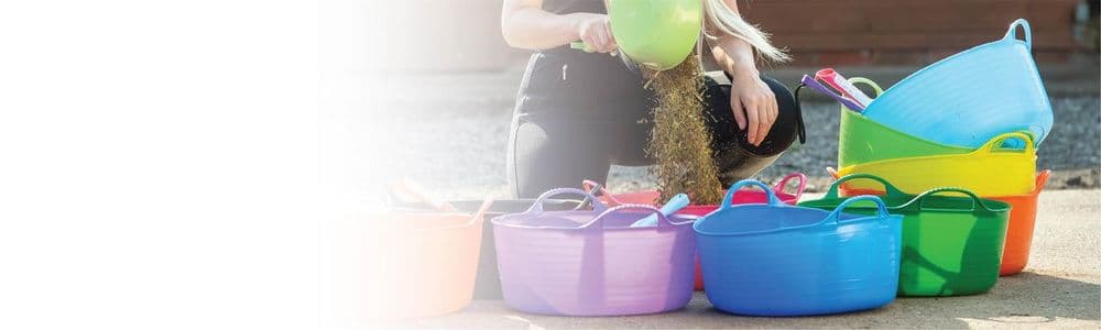 Multiple colourful Gorilla Tubs in use on a yard, being filled with feed